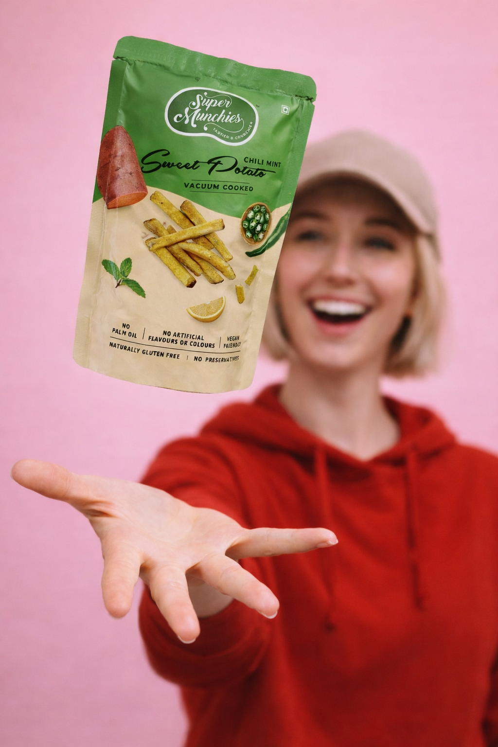 Person holding a Super Munchies Chili Mint Sweet Potato chips pack against a pink background