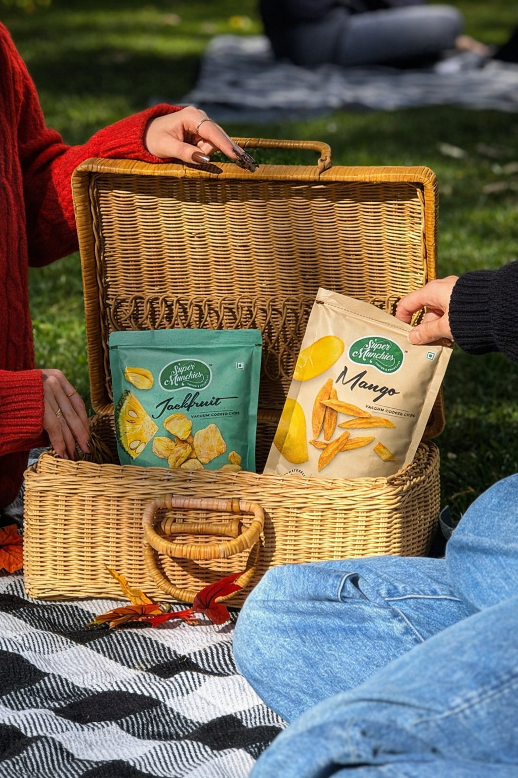 Picnic basket with Crunchy Jackfruit and Mango chips on a blanket outdoors