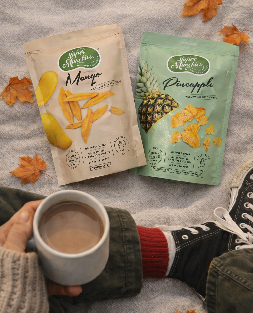 Outdoor picnic setting with Super Munchies mango and pineapple fruit chips and a cup of hot beverage