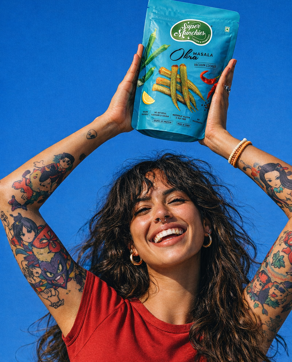 Person holding a Super Munchies Masala Okra chips pack against a bright blue background
